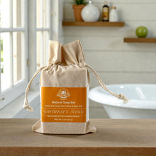 Load image into Gallery viewer, Bath Nutts Farmhouse raw milk &amp; tallow soap bar in a drawstring bag on a wooden surface with a bathroom background