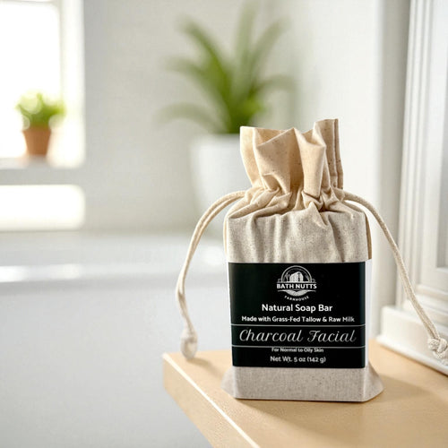 Bath Nutts Natural charcoal facial Soap Bar in a drawstring bag on a windowsill with plants in the background