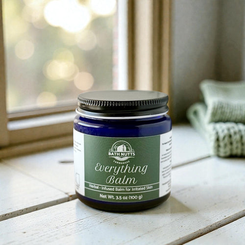 Bath Nutts Everything Balm jar on a wooden surface with a blurred background