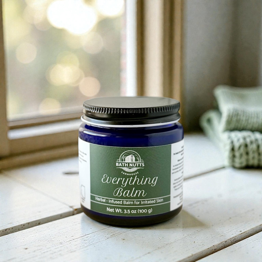 Bath Nutts Everything Balm jar on a wooden surface with a blurred background