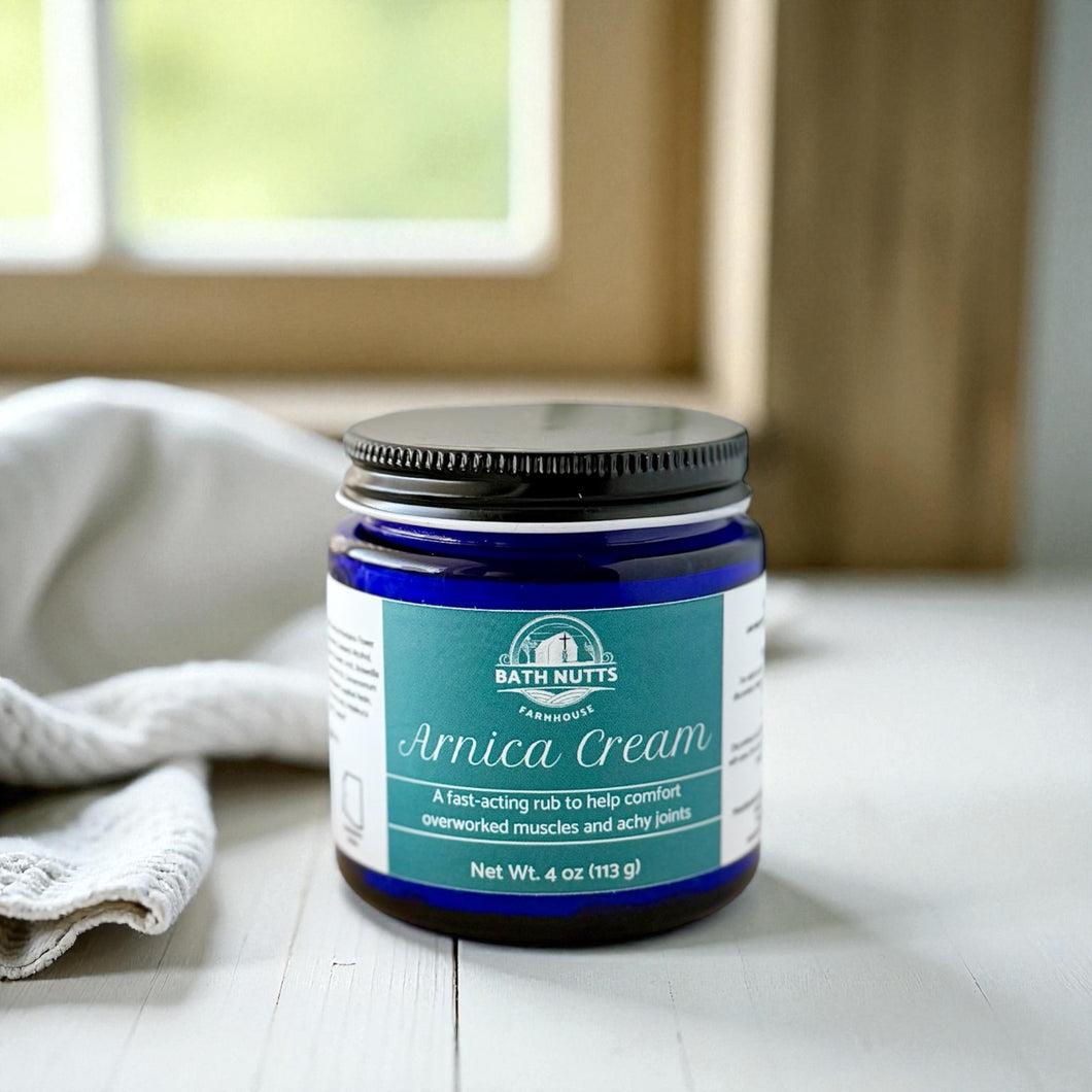 Bath Nutts Arnica Cream in a jar on a wooden surface with a blurred background