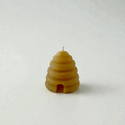 Beeswax candle shaped like a beehive on a white background